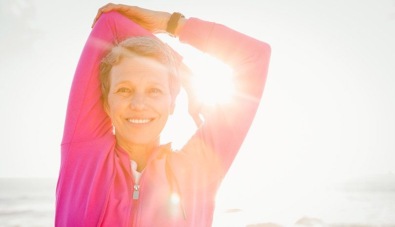 smiling middle-aged woman doing arms stretching